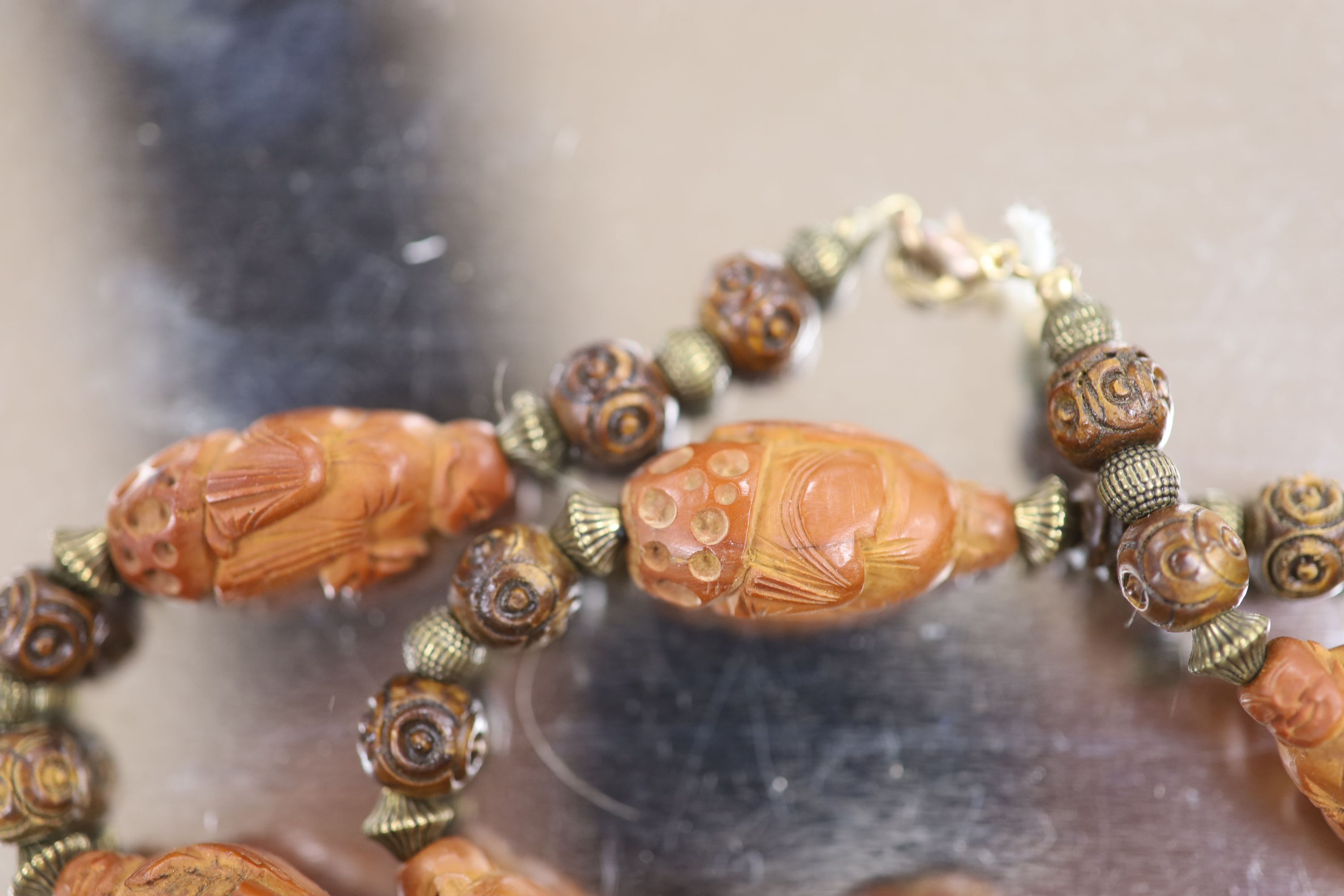 A Chinese peach stone or nut bead necklace, bracelet, a pair of earrings and two carved beads